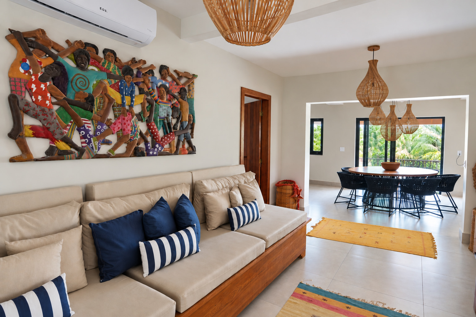 Bright communal lounge at a boutique hospitality property, featuring spacious sofa seating, colorful sculptural wall art, and an adjoining dining area.