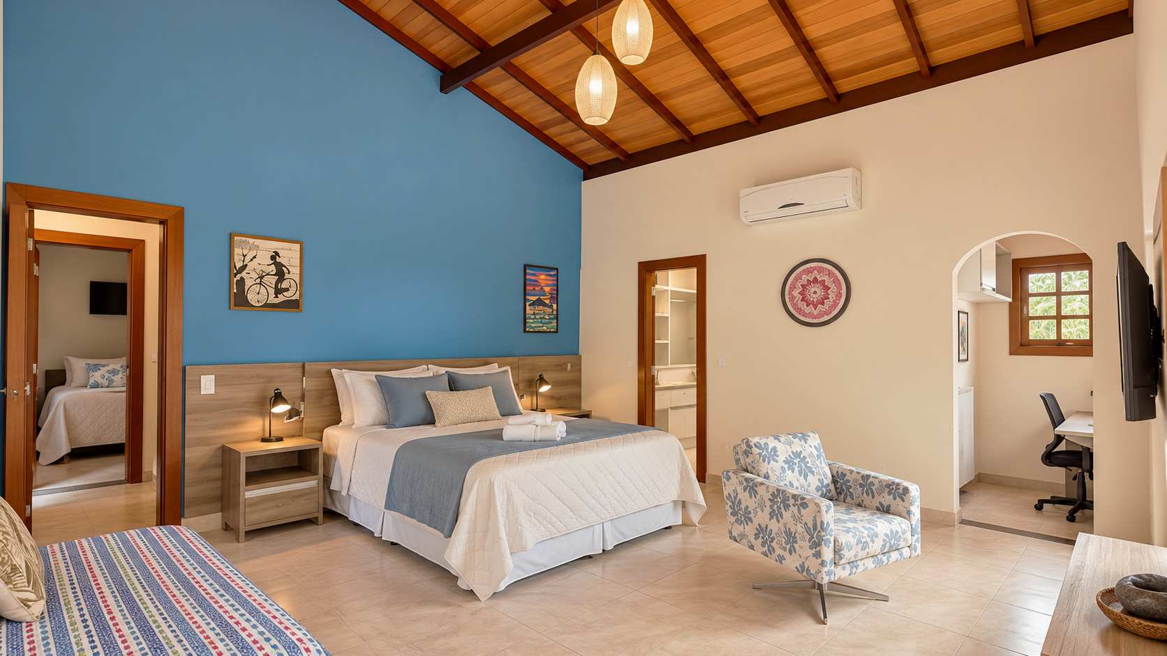 Großzügiges Schlafzimmer mit Meerblick, hoher Holzdecke, blauer Akzentwand, eigenem Badezimmer und Arbeitsbereich in einer exklusiven Ferienvilla.