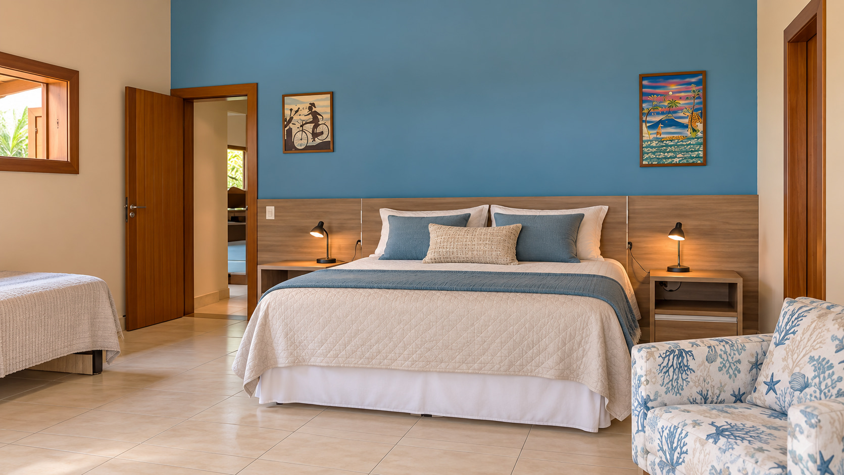 Großzügiges Schlafzimmer mit blauer Akzentwand, Doppelbett und zusätzlicher Schlafgelegenheit im Strandhaus mit Blick auf Pool und tropischen Garten.