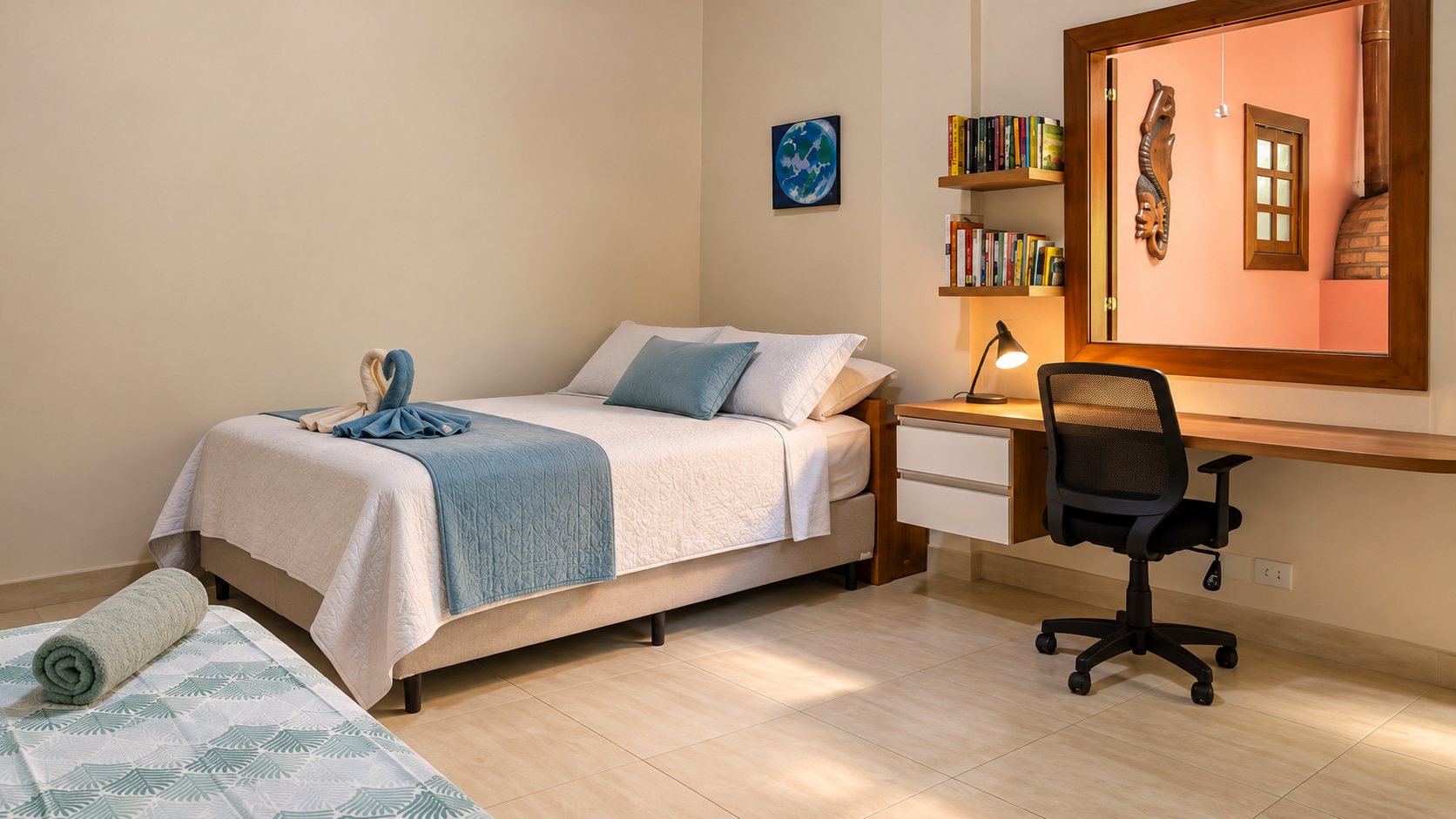 Helles Gästezimmer im Ferienhaus mit Doppelbett, zusätzlicher Schlafgelegenheit und integriertem Arbeitsbereich mit Bücherregalen.
