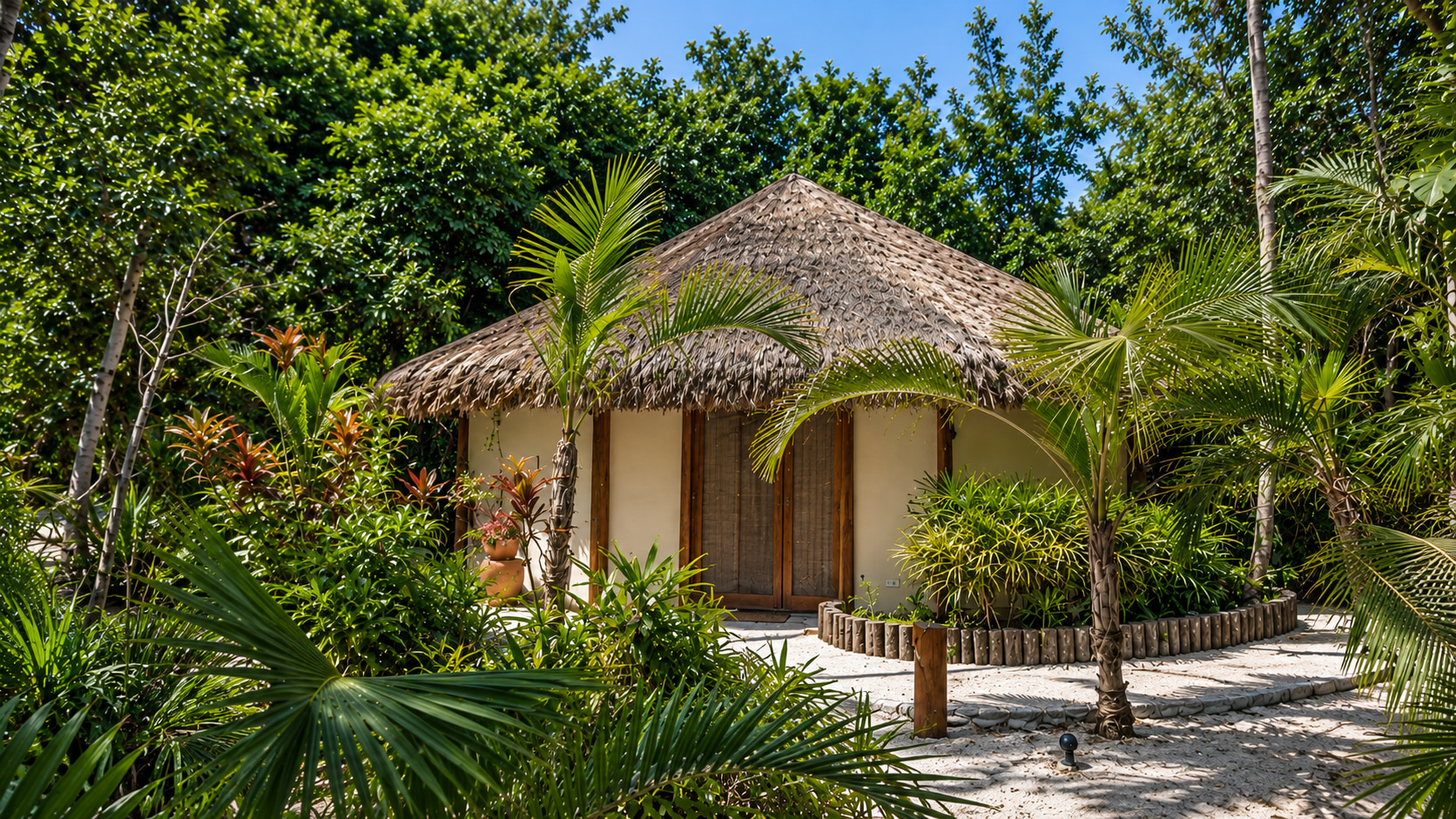 Charmantes Gästehaus der exklusiven Strandresidenz mit traditionellem Palmendach, Holztüren und üppiger tropischer Gartenlandschaft.